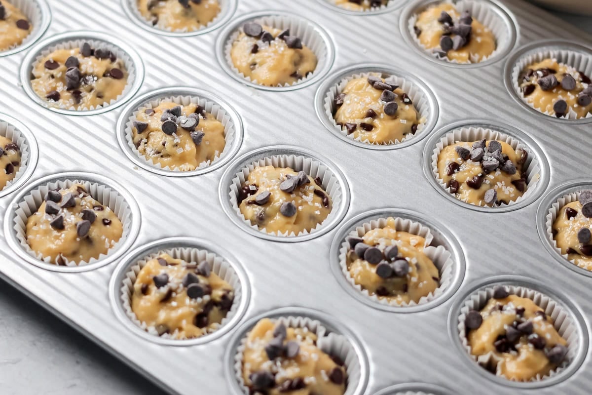 Mini Chocolate chips sprinkled onto muffin batter in pan.