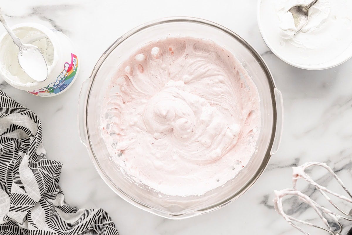 Creaming together cream cheese and strawberry preserves.