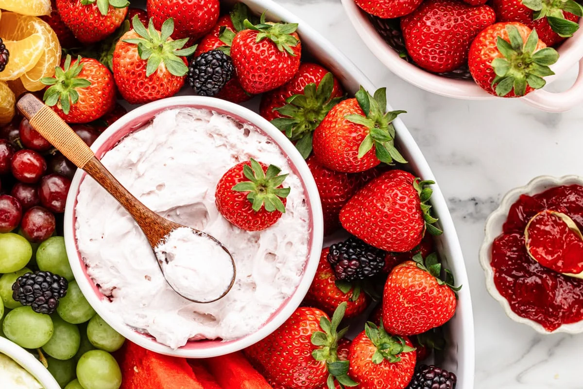 Strawberry fruit dip recipe in bowl with fruit all around.