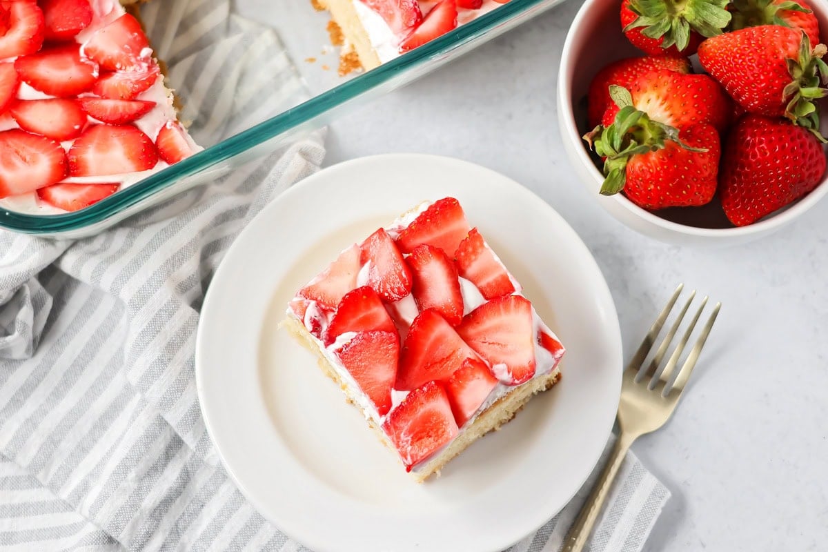 Strawberry shortcake bars on white plate with strawberries on the side.