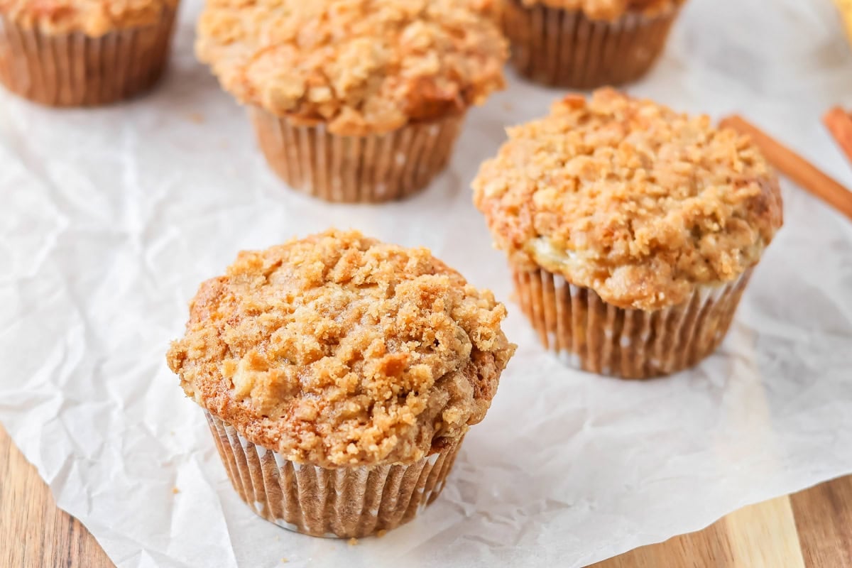Five banana crumb muffins on a crumpled parchment paper.