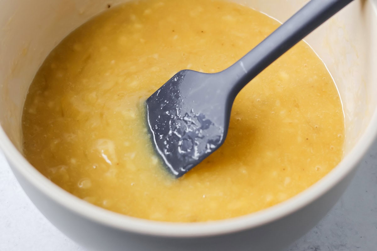 Adding melted butter to the banana muffin batter.