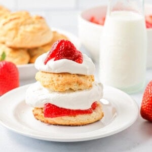 Bisquick strawberry shortcake recipe on plate with strawberries and biscuits in back.