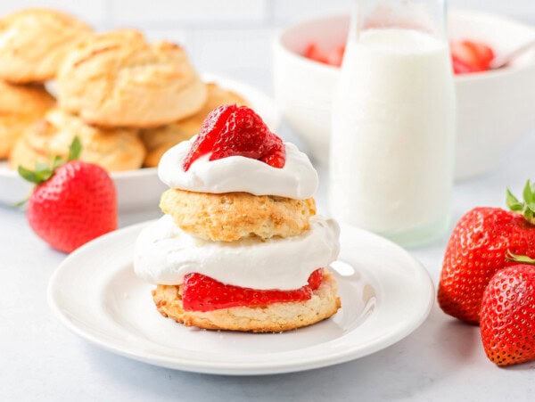 Bisquick strawberry shortcake recipe on plate with strawberries and biscuits in back.
