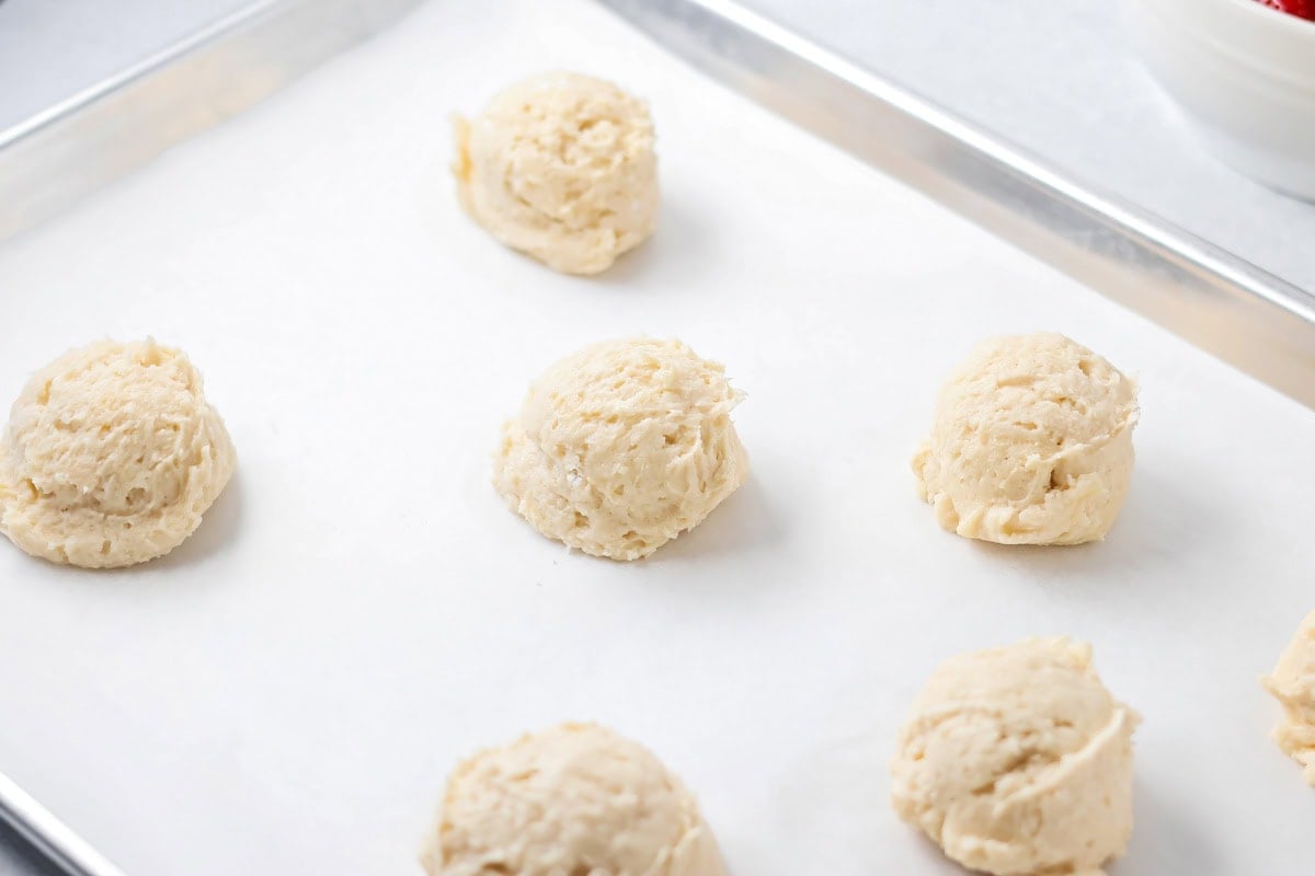 Biscuit drops on a lined baking sheet.
