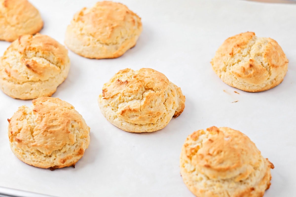 Cooked biscuits on a lined baking sheet.