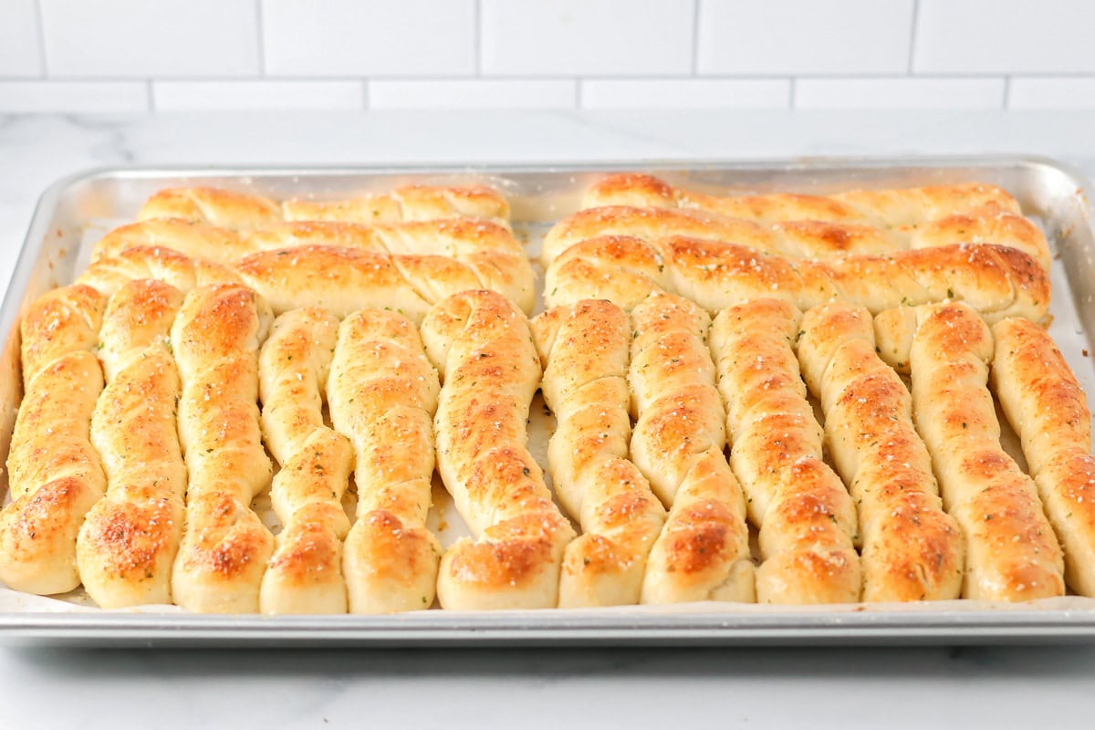 Cooked breadsticks topped with seasonings.