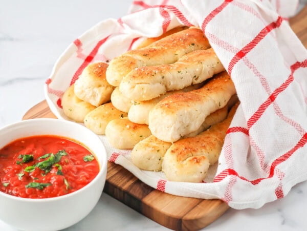 Homemade breadsticks served in a basket.