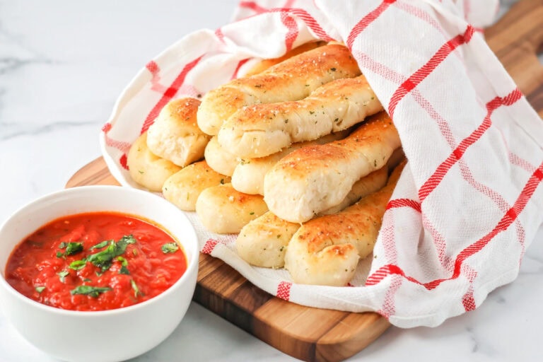Homemade breadsticks served in a basket.