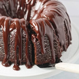 Brownie Cake recipe on cake stand with a slice being served.
