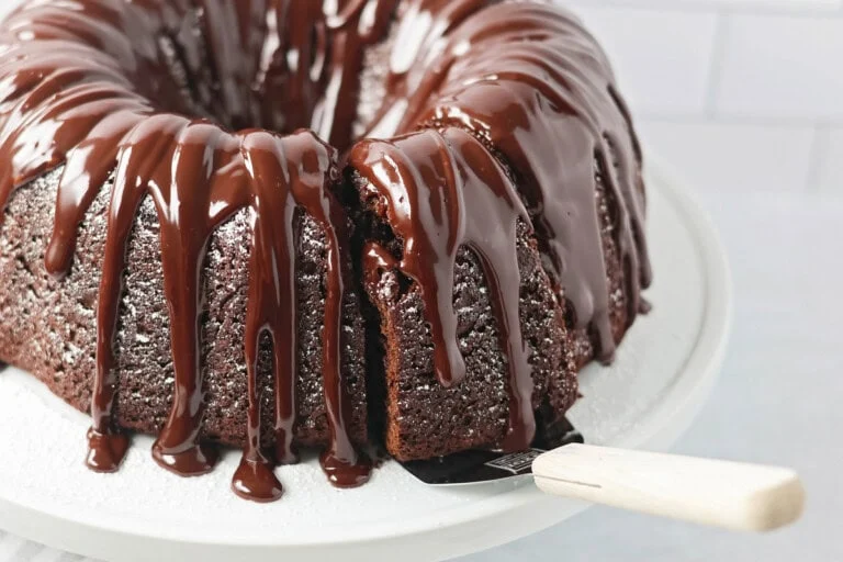 Brownie Cake recipe on cake stand with a slice being served.
