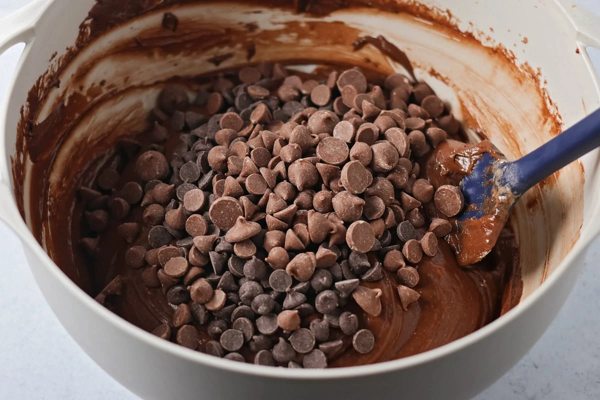 Adding chocolate chips to batter in mixing bowl.