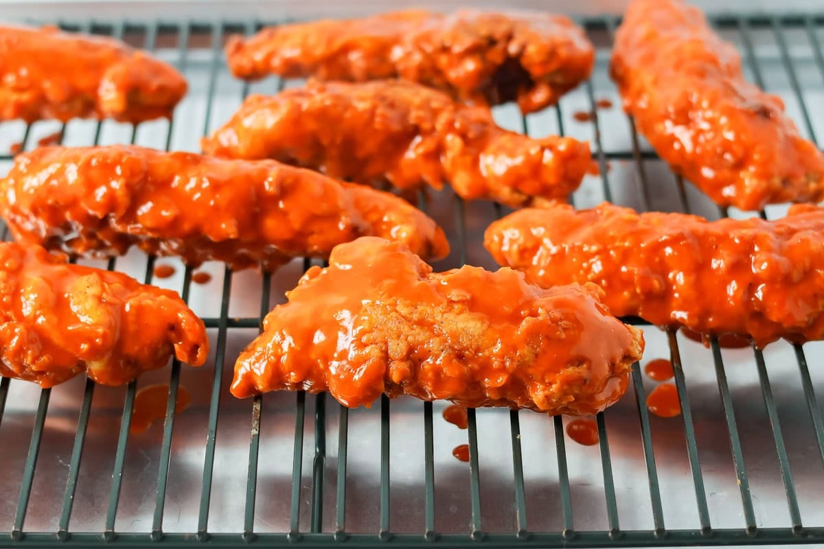 Buffalo chicken tenders ripping on a cooling rack.