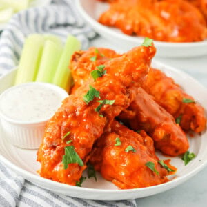 A plate of buffalo chicken tenders served with celery and dipping sauce.