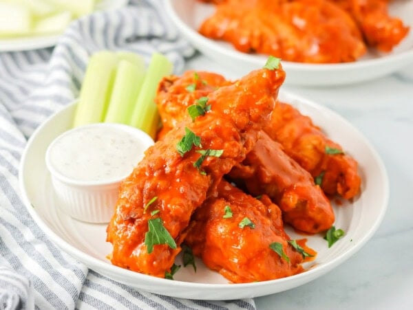 A plate of buffalo chicken tenders served with celery and dipping sauce.