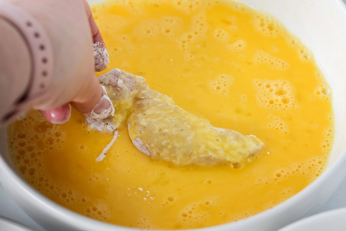 Dipping buffalo chicken tenders into the buttermilk mixture.