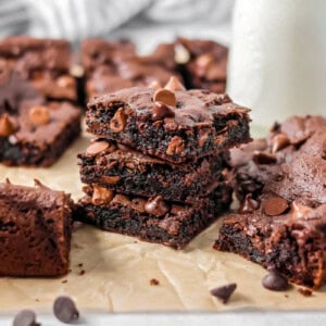 Cake Mix Brownies stacked on each other with glass of milk in the background.