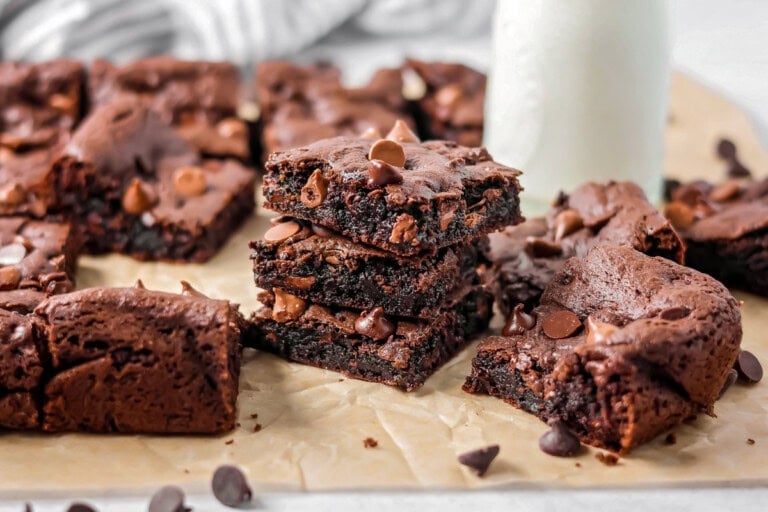 Cake Mix Brownies stacked on each other with glass of milk in the background.