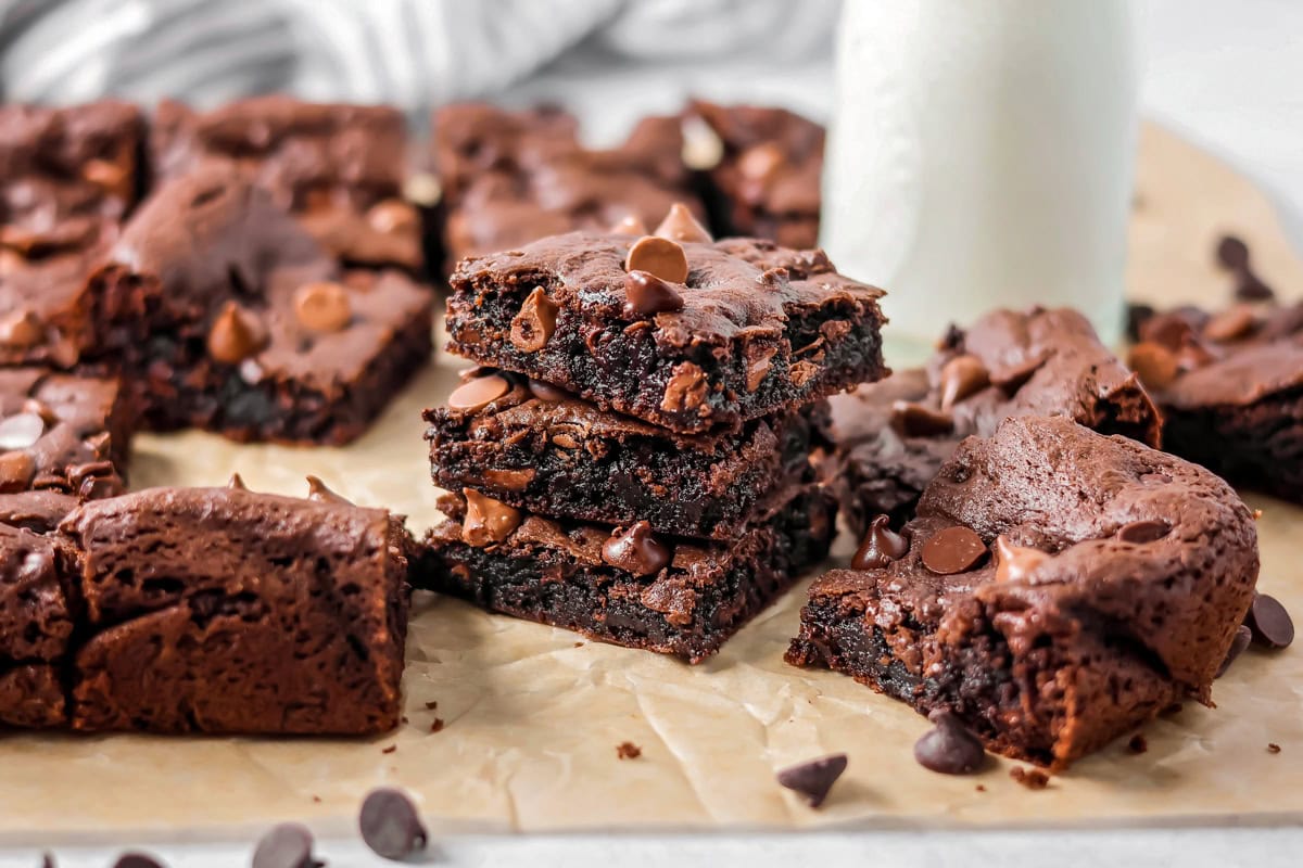 Cake Mix Brownies stacked on each other with glass of milk in the background.