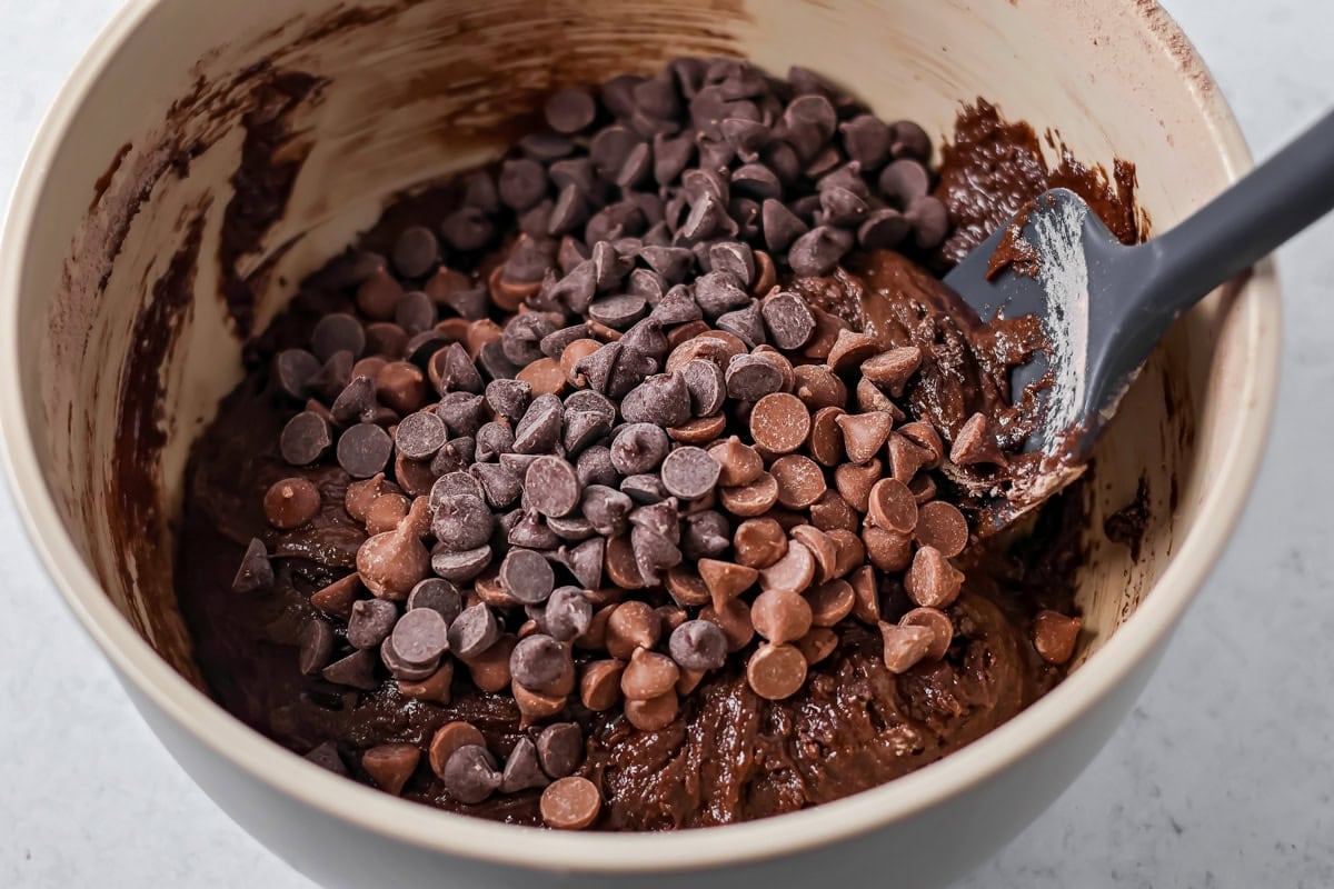 Adding chocolate chips to cake mix brownies batter.