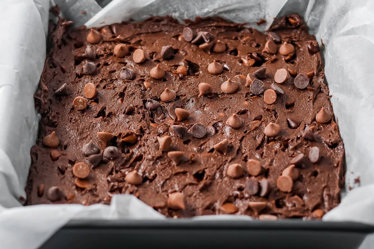 Chocolate chips sprinkled on cake mix brownies batter.