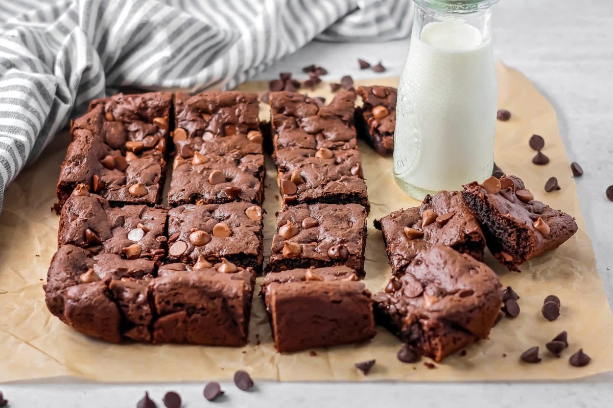 Cake mix brownies cut on parchment paper with glass of milk.