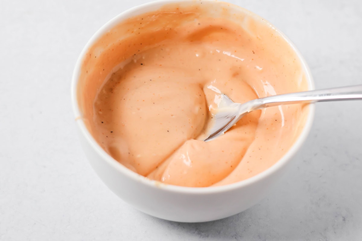 Mixing cane's sauce in a white bowl.
