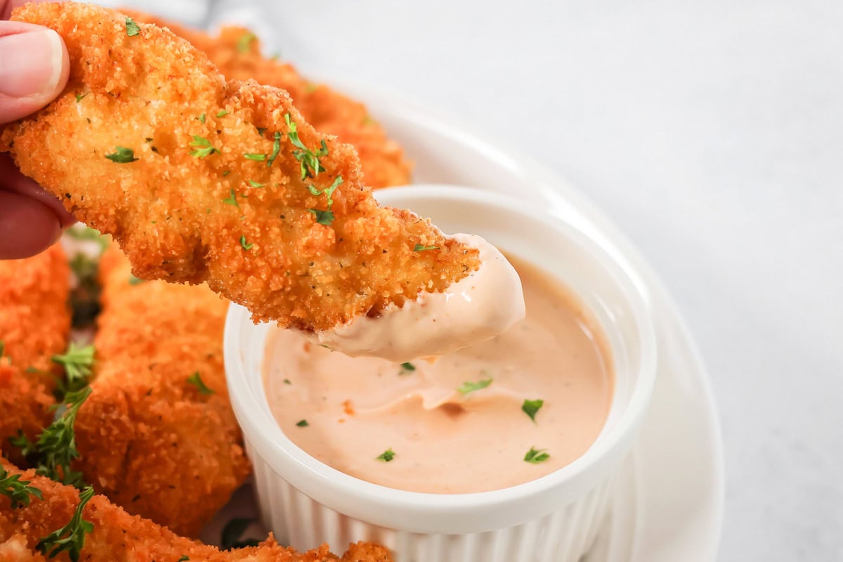 Dipping chicken tender in cane's sauce.