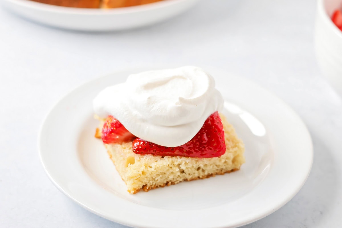 Layering strawberries and whipped cream on a shortcake layer.
