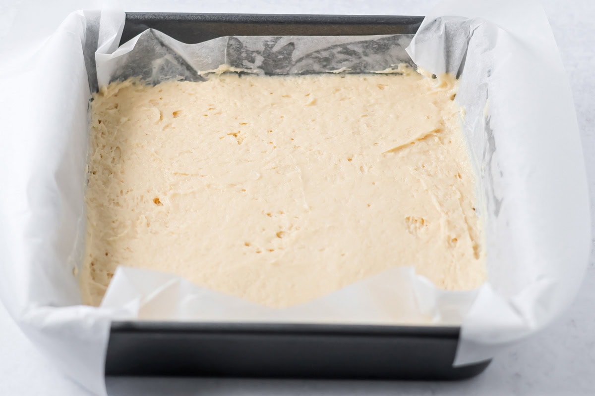 Spreading shortcake batter in a lined baking dish.