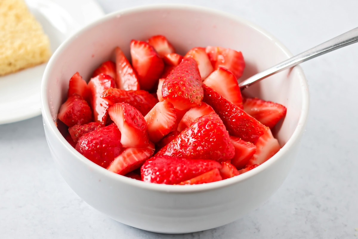 Strawberries and sugar in a white bowl.