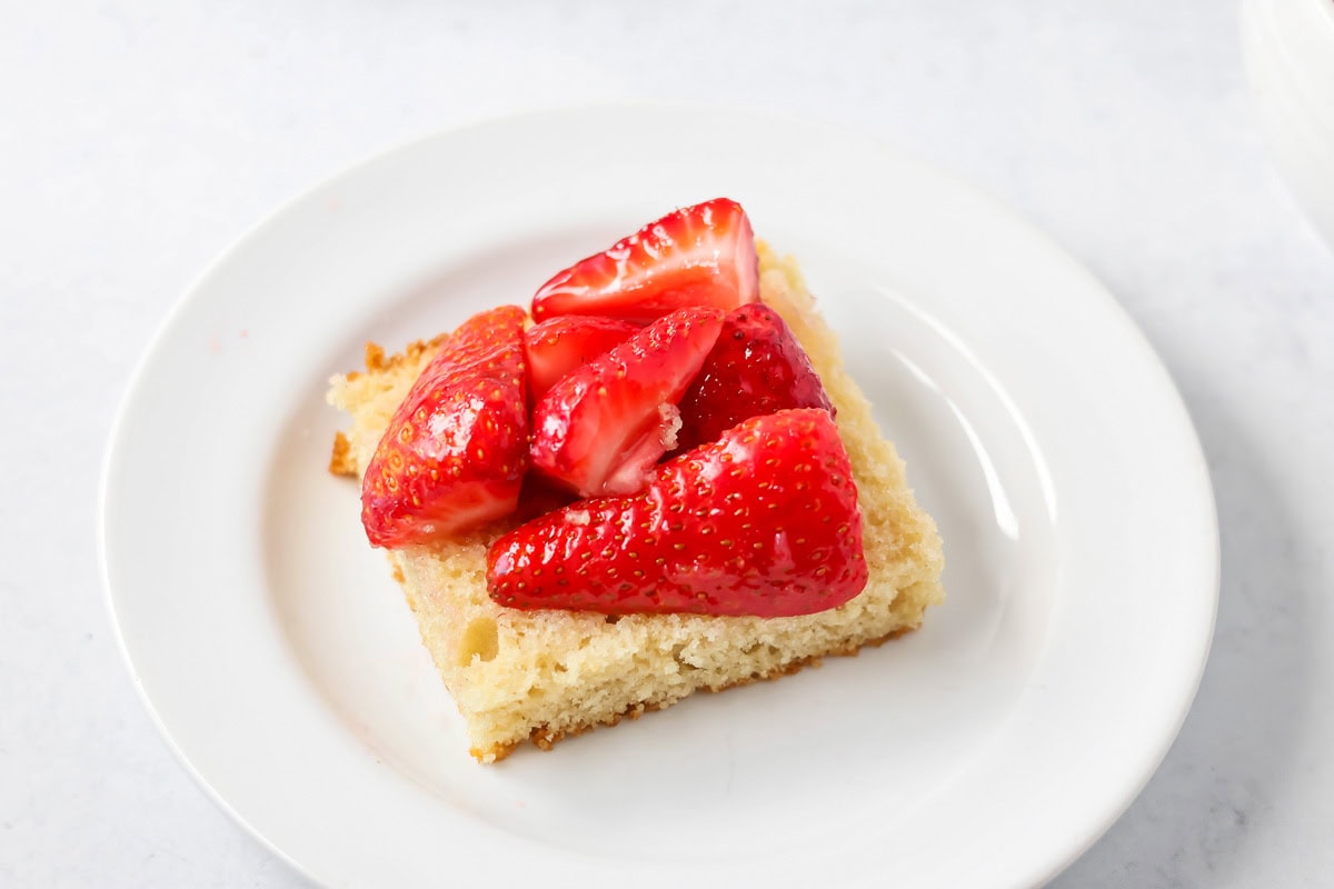 Adding strawberries to the top of a shortcake layer.