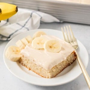 A slice of easy banana cake frosted and topped with fresh banana slices.