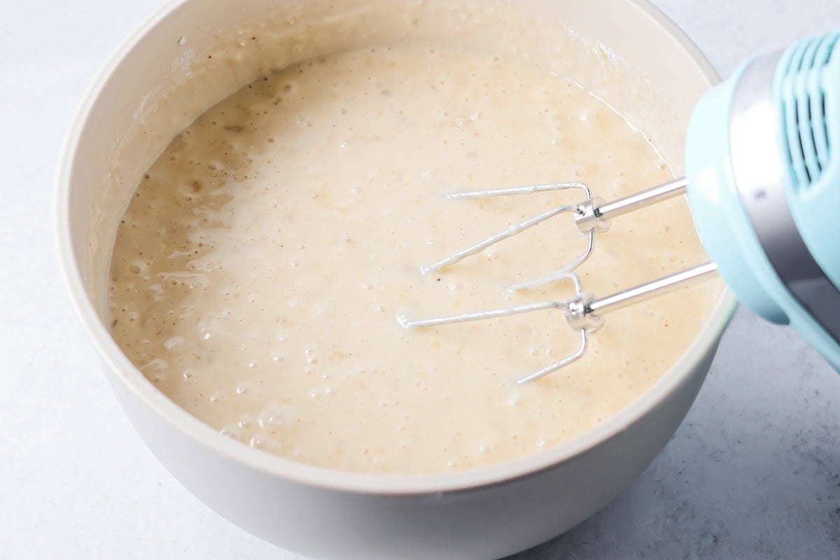 Mixing batter for easy banana cake in a white bowl.