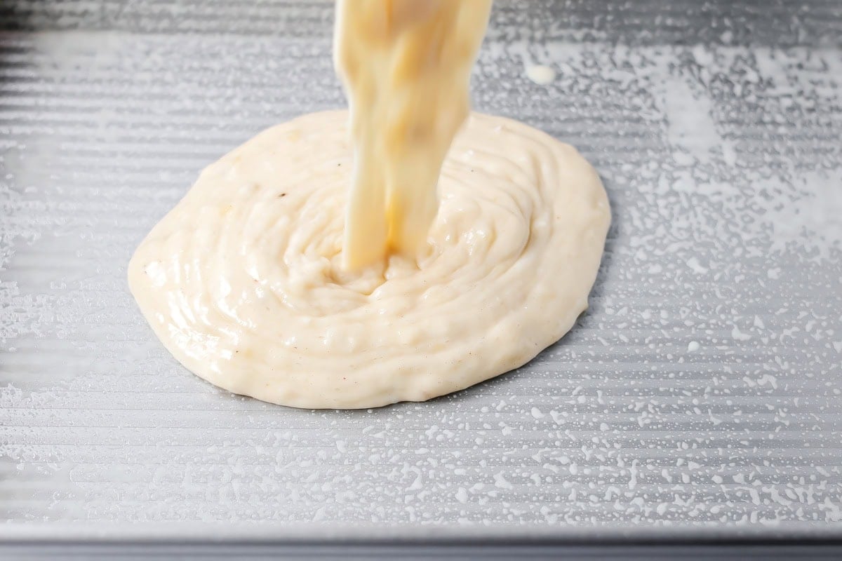 Pouring banana cake batter in a baking dish.