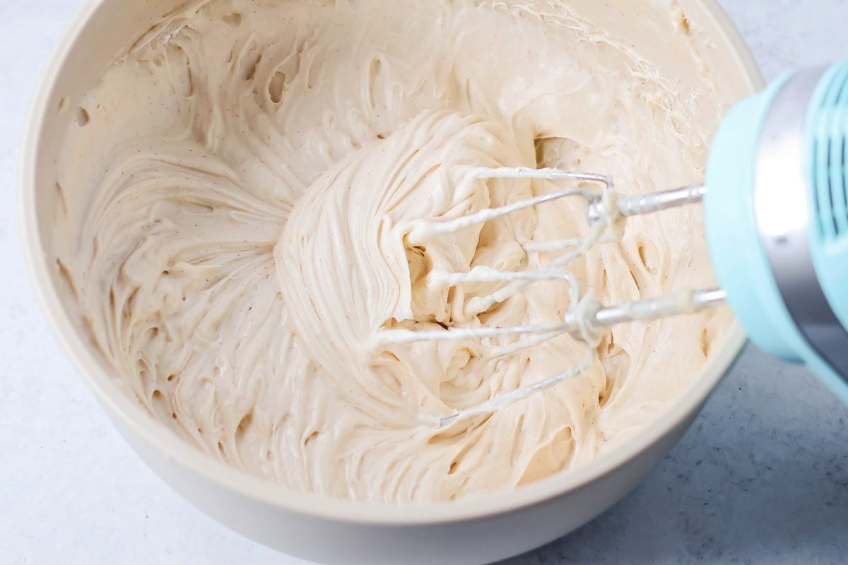 Whipping banana cake frosting in a white bowl.