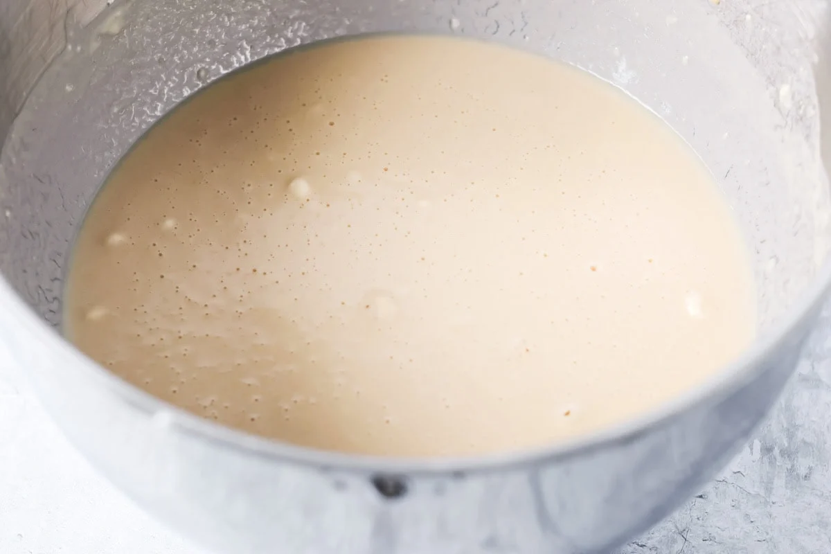 Bread dough ingredients in a metal bowl.