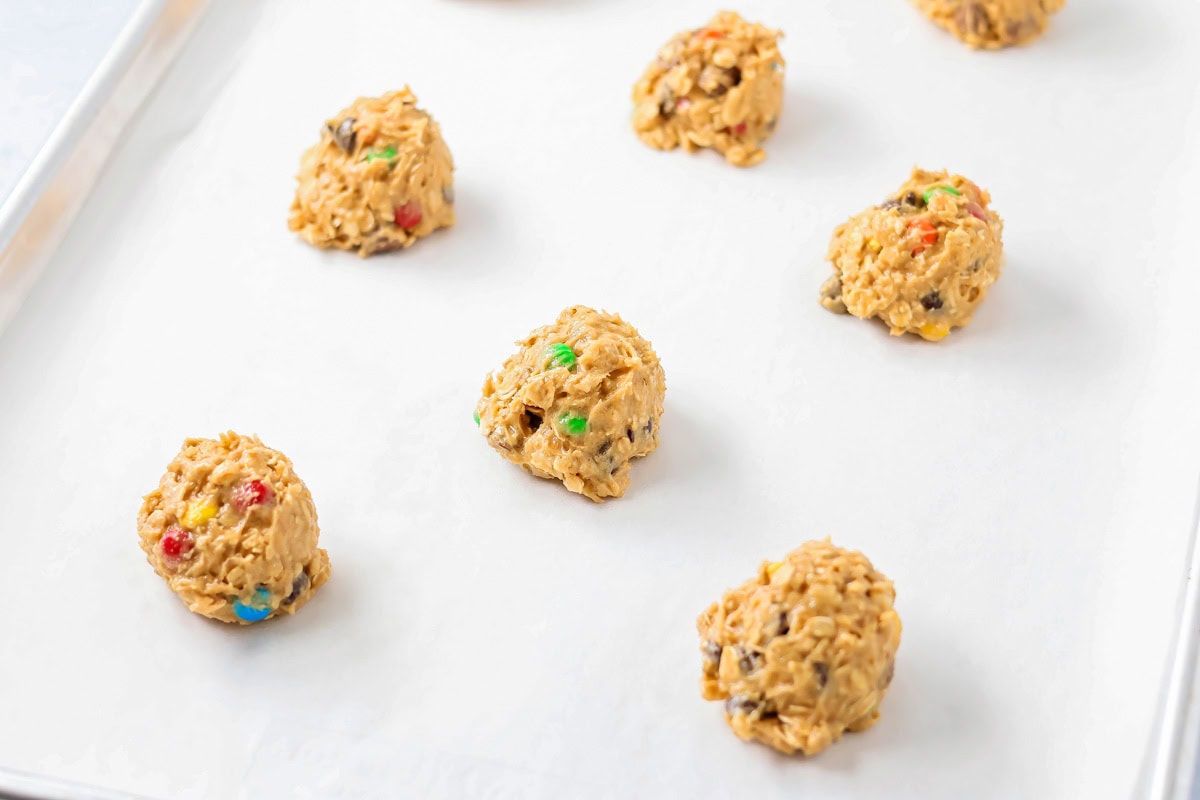Cookie dough balls on a lined baking sheet.