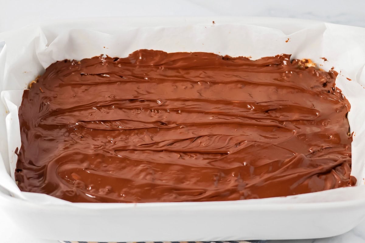 Spreading the chocolate on top of the mounds bar recipe.