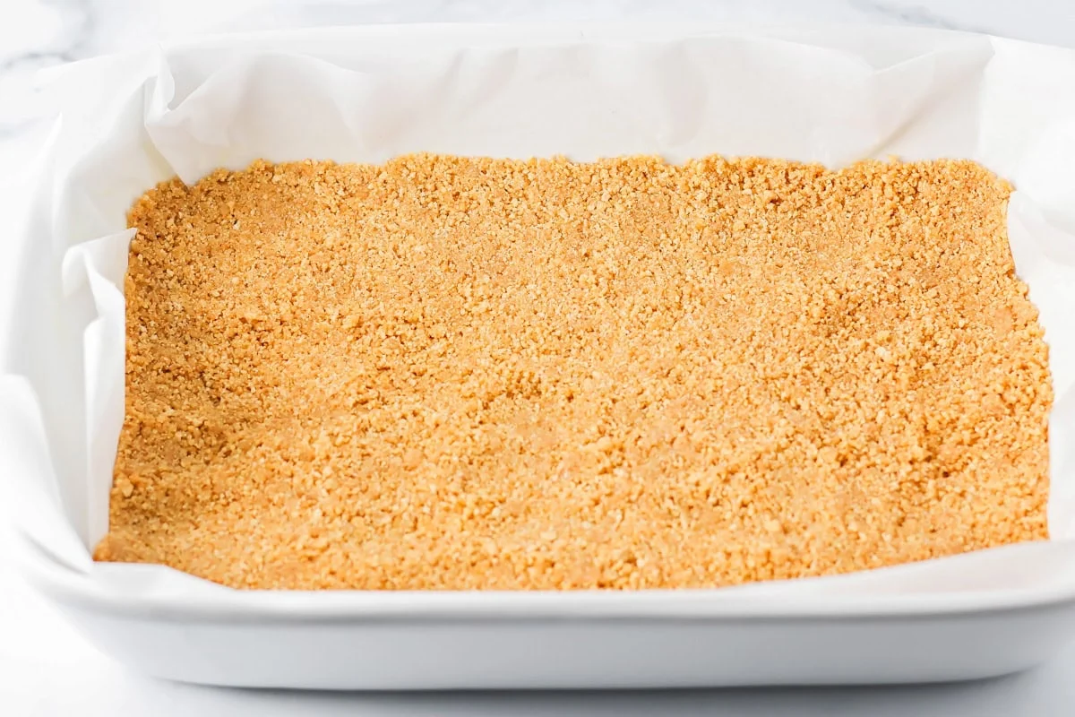 Pressing the graham cracker crust into the bottom of a baking dish for mounds bars.