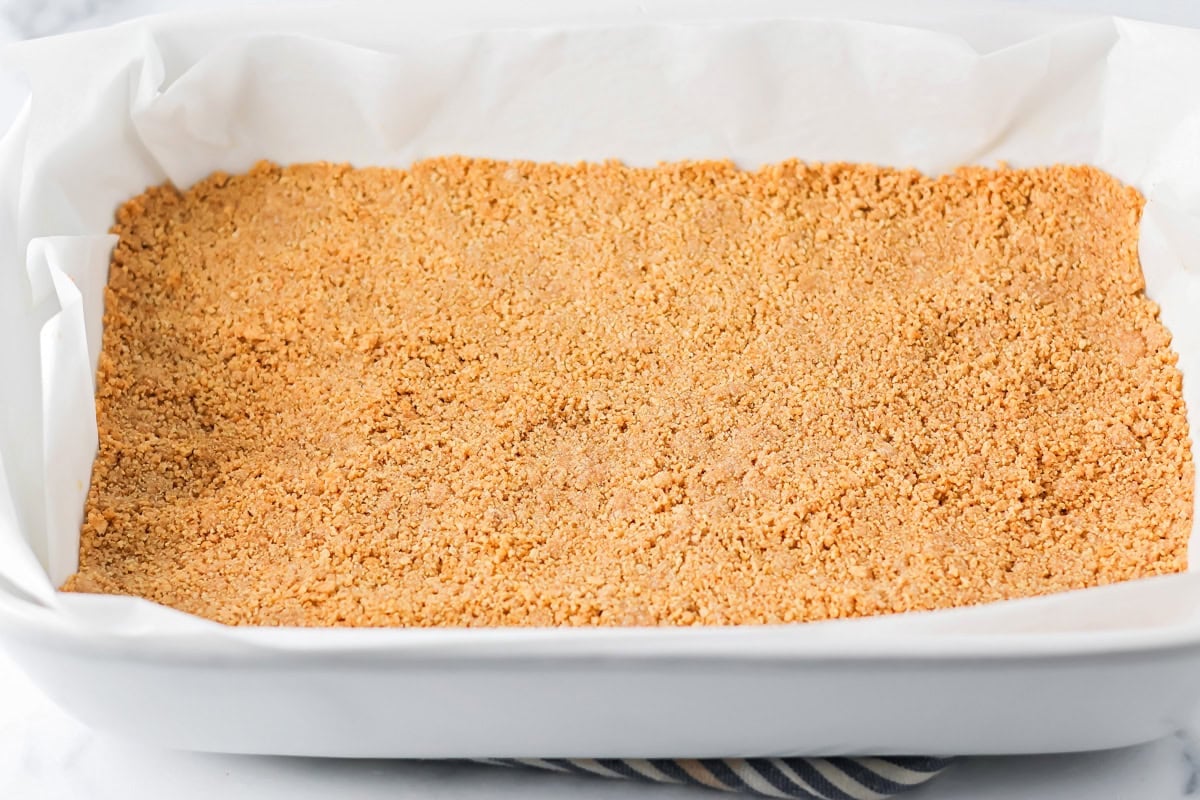 Graham cracker crust in a baking dish for mounds bars.