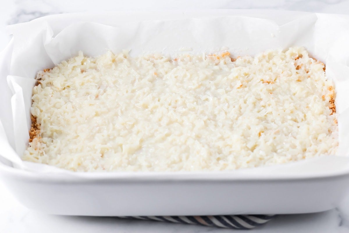 Layering coconut in a pan for mounds bar recipe.
