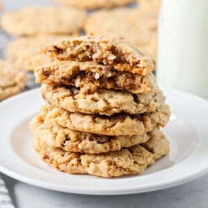 A stack of oatmeal toffee cookies stacked on a white plate.