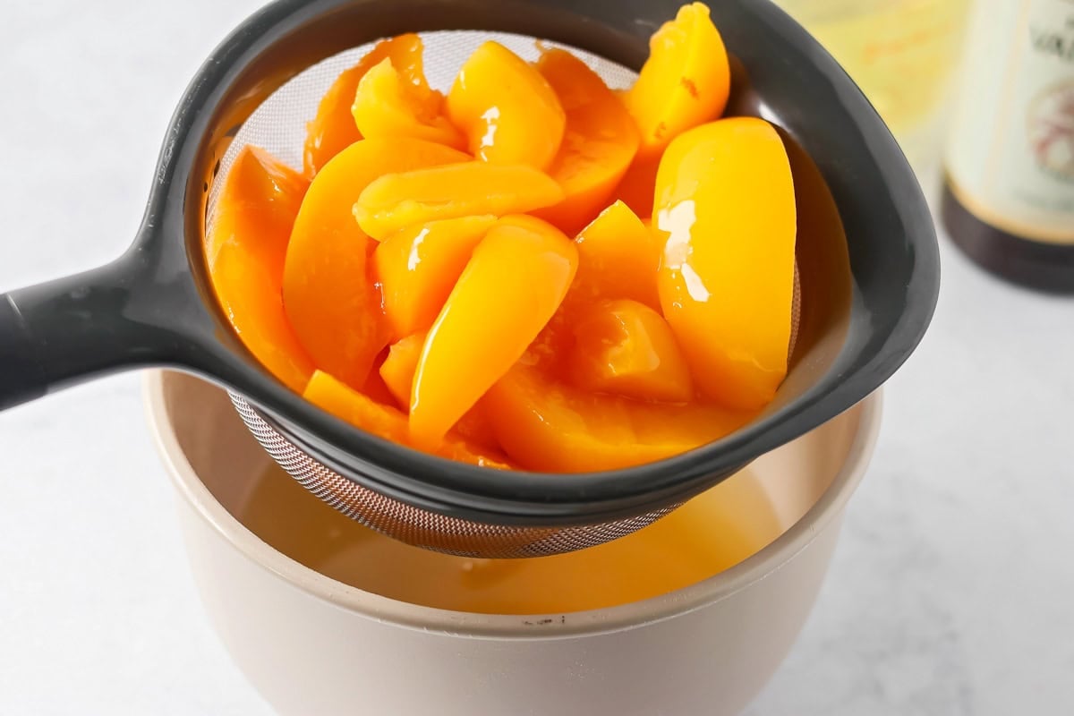 Draining peaches for peaches and cream cake recipe.