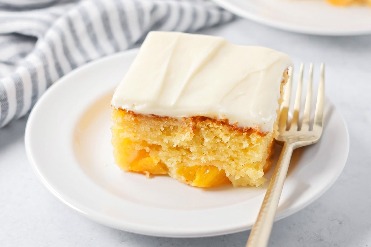 A slice of peaches and cream cake on a white plate.
