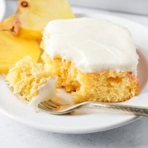 A slice of frosted easy pineapple cake with a bite missing.