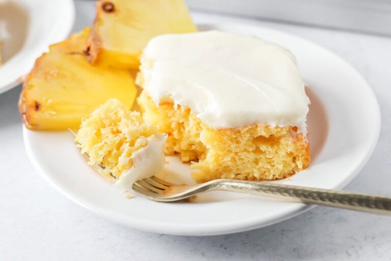 A slice of frosted easy pineapple cake with a bite missing.