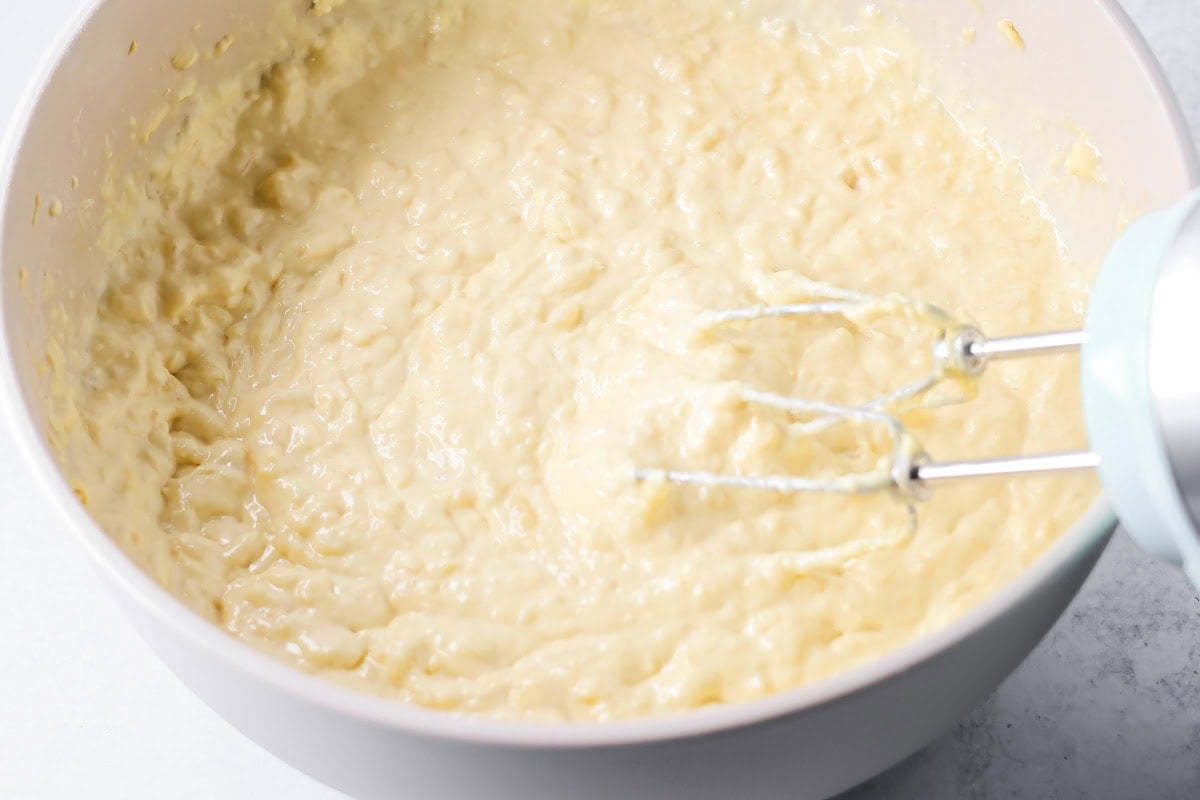 Mixing pineapple cake batter in a white bowl.