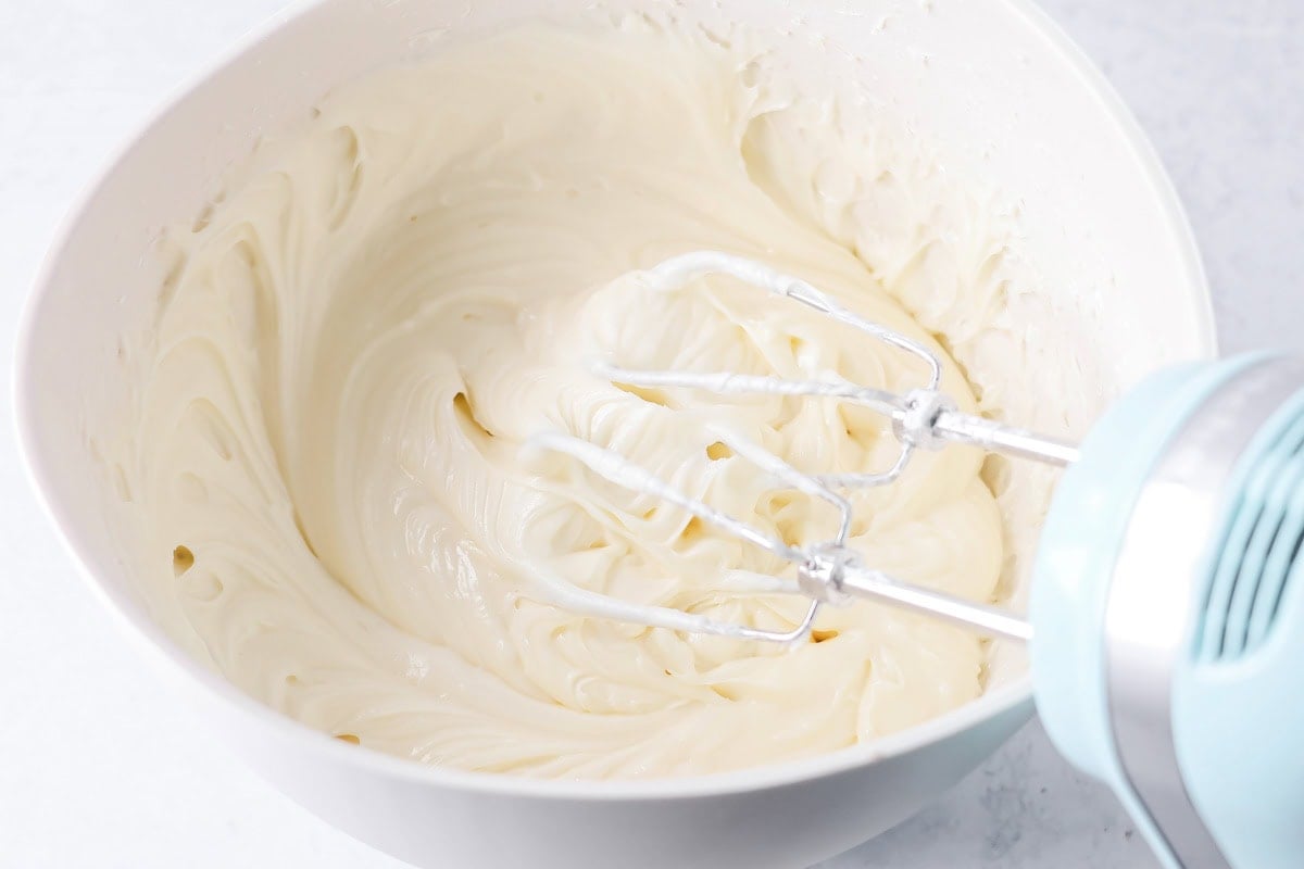 Whipping pineapple cake frosting in a white bowl.
