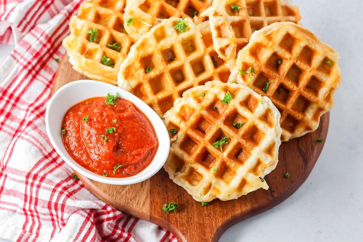 Several Pizza waffles served with marinara sauce.